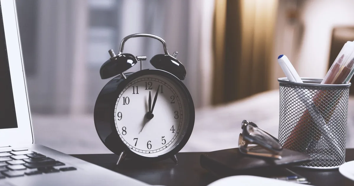 Budzik na biurku przy laptopie, symbol zauważania godziny 14:41