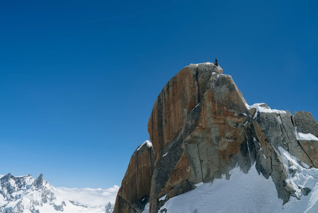 Wspinacz na ośnieżonym szczycie w masywie Mont Blanc – cel osiągnięty krok po kroku, jak przy ascendencie w Koziorożcu