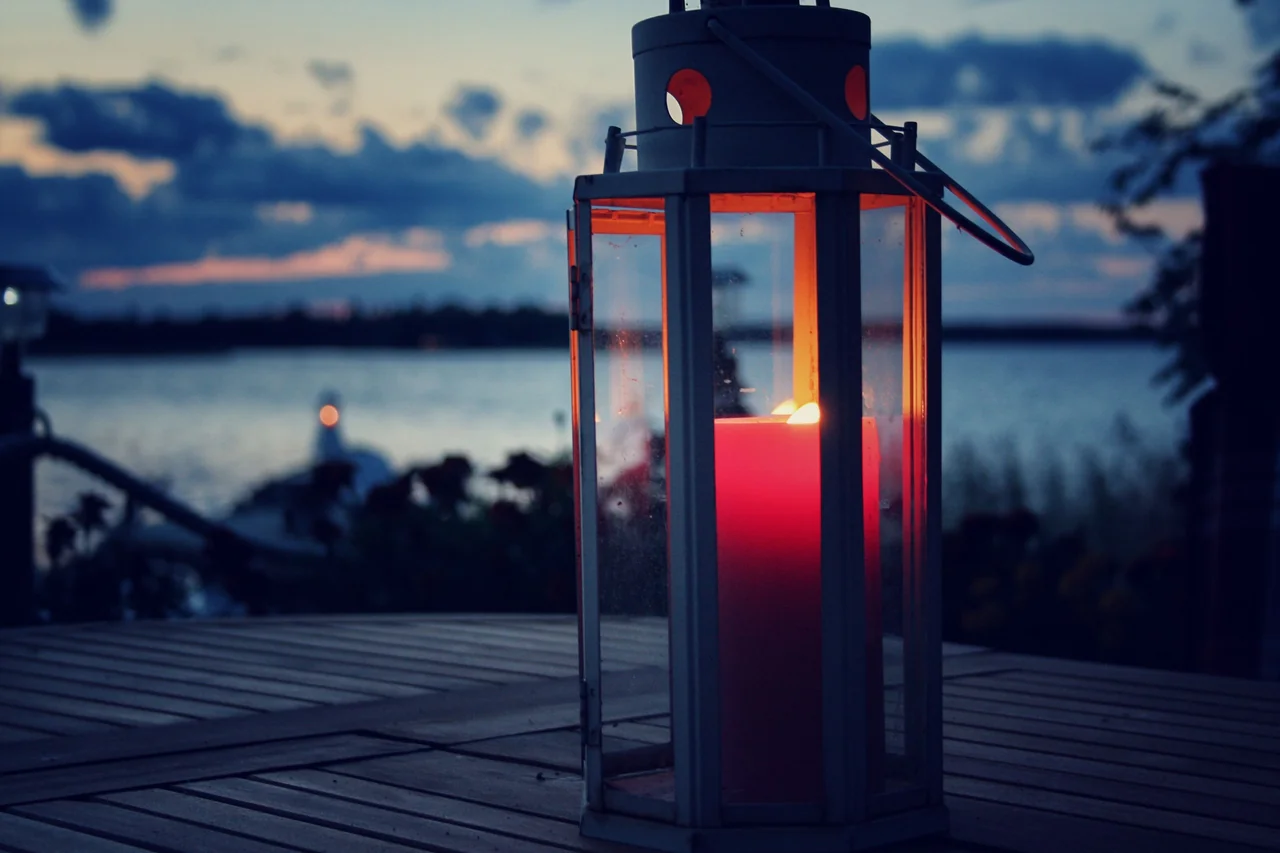 Lampion ze świecą na pomoście nad wodą – ogień Strzelca obok wody Raka, znaki w kwinkunksie